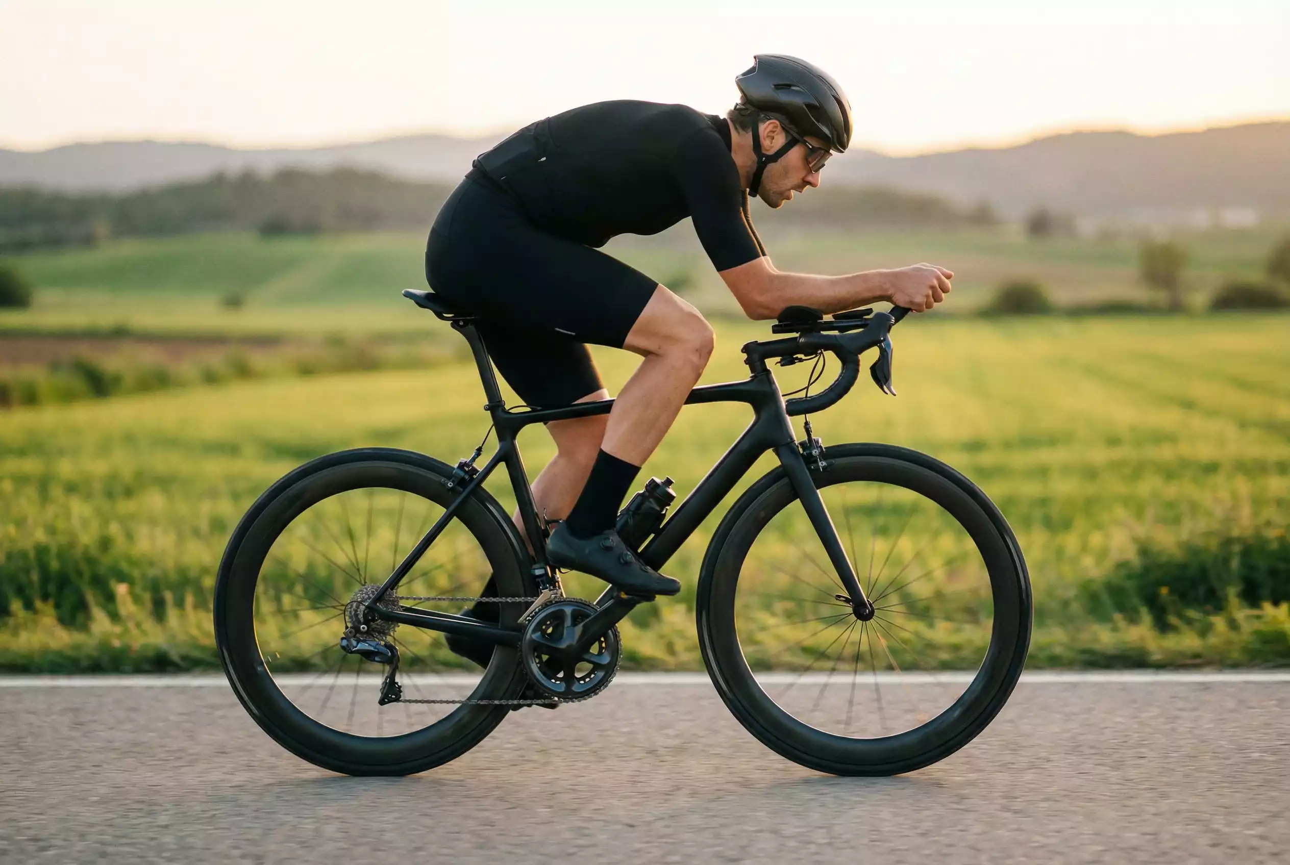 Ciclista profesional entrenando en carretera con un ciclocomputador mostrando datos de rendimiento